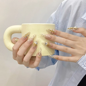 Luxurious handmade press-on nails with gold foil, pearls, and rhinestones in almond shape