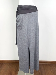 Detail view of grey knitted maxi skirt featuring a high-waisted contrast panel and side slit