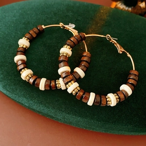 Detail of bohemian hoop earrings with wood beads on dark green velvet cushion