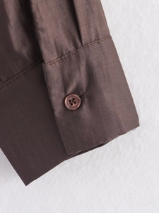Detailed macro view of the dark brown shirt cuff showing texture and a matching button