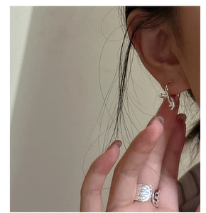 Detail of s925 silver knot earrings and wide textured open ring on model