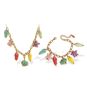 Gold ocean theme necklace and colorful ceramic fish bracelet set on white background