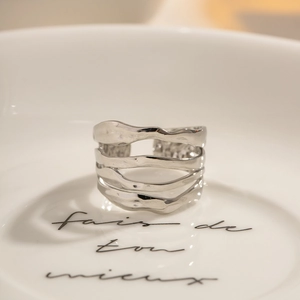 Minimalist silver multilayer wavy open ring in polished stainless steel on white plate