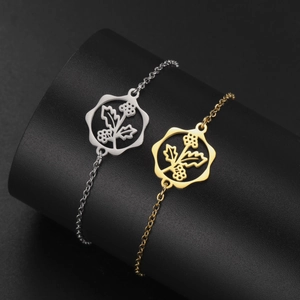 Macro shot of gold and silver hollow floral pendants on a minimalist steel chain bracelet