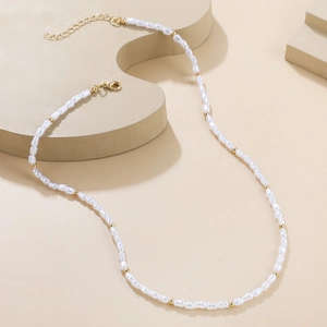 Baroque pearl necklace with irregular white pearls and gold beads on minimalist beige stand