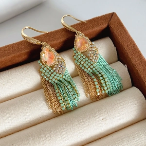Detail of bohemian gold tassel earring with orange teardrop stone and turquoise beads