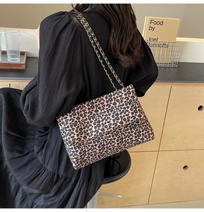 Detail of leopard print shoulder bag with gold chain strap in a stylish cafe setting