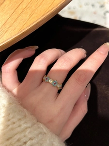 Detail of 18k gold plated flower ring with blue and red zircon petals on a finger