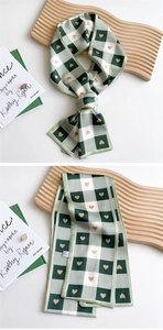 Detail of green checkerboard skinny silk scarf with heart pattern and smooth texture