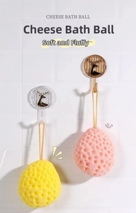 Detail of cheese-shaped honeycomb bath sponges in yellow and pink hanging on hooks