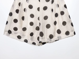 Close-up of white fabric with black polka dots showing breathable texture and hem