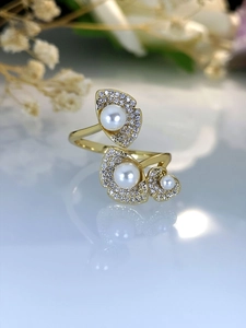 Detailed view of gold lotus leaf ring with inlaid pearls and zircon on reflective surface