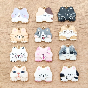 Macro view of twelve assorted enamel cat charms with diverse expressions on wood