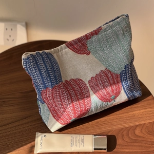 Retro pumpkin jacquard makeup bag with colorful tulip patterns on a wooden table