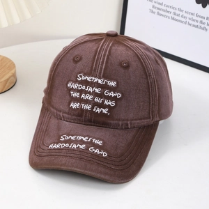 Makro-Detail einer dunkelbraunen Vintage-Baseballkappe mit weißer Buchstabenstickerei