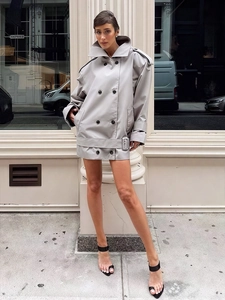 Detail of grey double-breasted trench coat with glossy finish and lapel collar design
