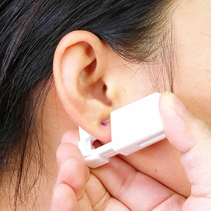 Single-use stainless steel ear piercing tool being used on an earlobe professionally