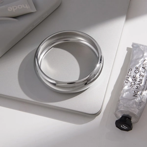 Polished silver stainless steel chunky bangle on an elegant minimalist laptop background