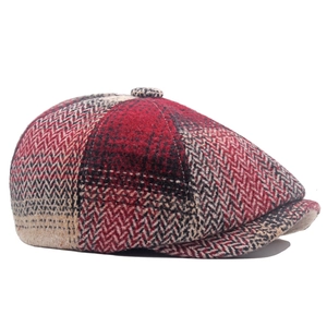 Close-up of red herringbone newsboy cap featuring wool texture and decorative top button