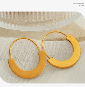 Macro shot of minimalist gold hoop earrings on textured fabric in Nordic style