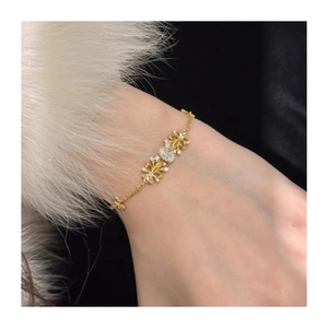 Detailed view of gold fleur-de-lis chain bracelet with pavé cubic zirconia on wrist