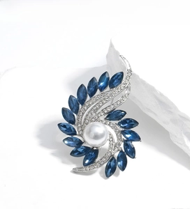 Detail of a rotating flower brooch with dark blue crystals and a white center pearl