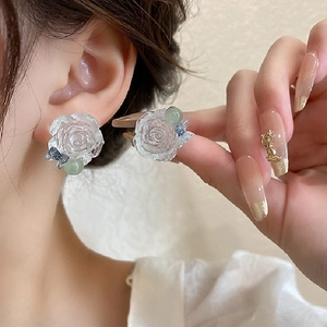 Detailed close-up of transparent resin rose earrings with blue bows and green beads