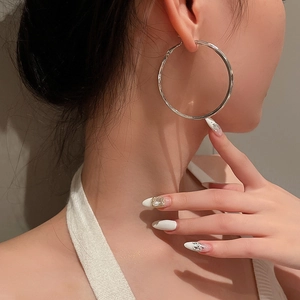 Close-up of a large silver hoop earring worn by a model for a chic minimalist look