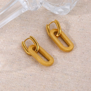 Macro detail of interlocked golden U-shaped earrings with fine horizontal textures