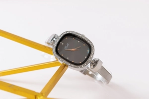 Detail of silver mesh strap watch with diamond-set bezel and black sunray dial