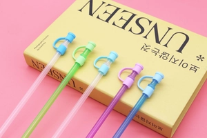 Detailed view of colorful reusable silicone straw covers set on a yellow book background