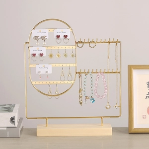 Golden metal jewelry stand with wooden base displaying earrings and necklaces