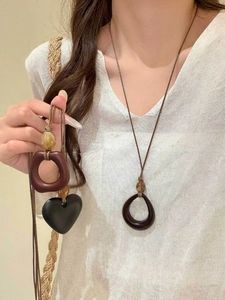 Macro detail of irregular resin pendants on wax cord necklace worn by a model