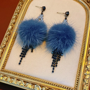 Macro shot of blue pompom earrings with sparkling rhinestone tassels on gold frame