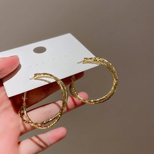 Detailed shot of double-layered gold hoop earrings with irregular twisted texture on card