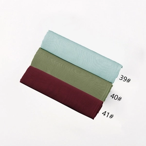 Close-up of stacked modal cotton hijabs in light cyan, olive green, and dark maroon colors