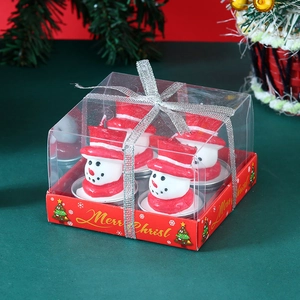 Close-up of four snowman Christmas candles in a red gift box with a silver ribbon bow