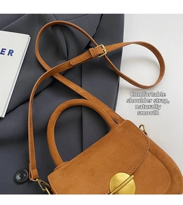Detail of adjustable strap and vintage gold buckle on brown suede saddle bag