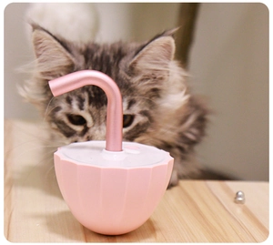 Pink automatic pet water fountain with metal nozzle on a cozy wooden table background