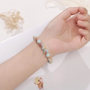 Détail d'un bracelet en perles de pierre naturelle au poignet avec texture bleu et beige