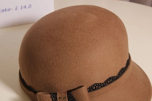 Detail of wool cloche hat showing caramel brown felt texture and floral lace trim