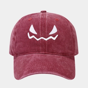 Close-up of funny monster face embroidery on a washed burgundy cotton baseball cap