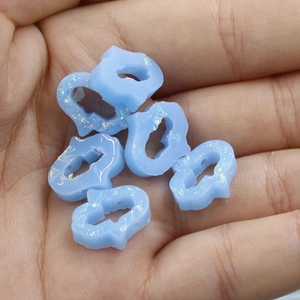 Macro shot of light blue cloud-shaped opal beads with iridescent glitter for DIY jewelry