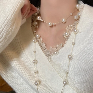 Detail of layered pearl necklace featuring varied bead sizes and golden chain links