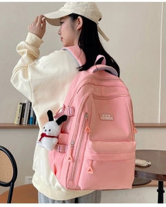 Detail of pink waterproof school backpack featuring a plush bunny charm and DBX metal logo