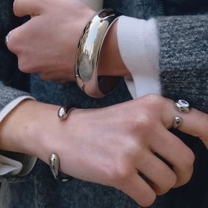 Polished silver bangle and ring set with fluid metal design on a model's wrist