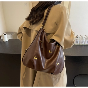 Detail of a deep coffee PU leather Hobo bag with golden butterfly metal ornaments
