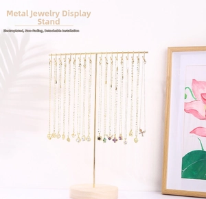 Detail of gold metal necklace stand with plating finish and a natural round wooden base