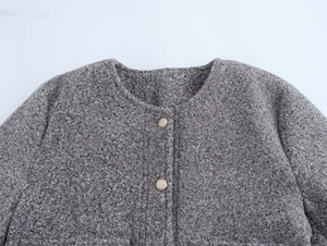 Détail de la veste bouclée grise avec boutons dorés vintage et tissu texturé