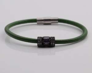 Detail of green leather bracelet with purple gemstone charm and magnetic clasp
